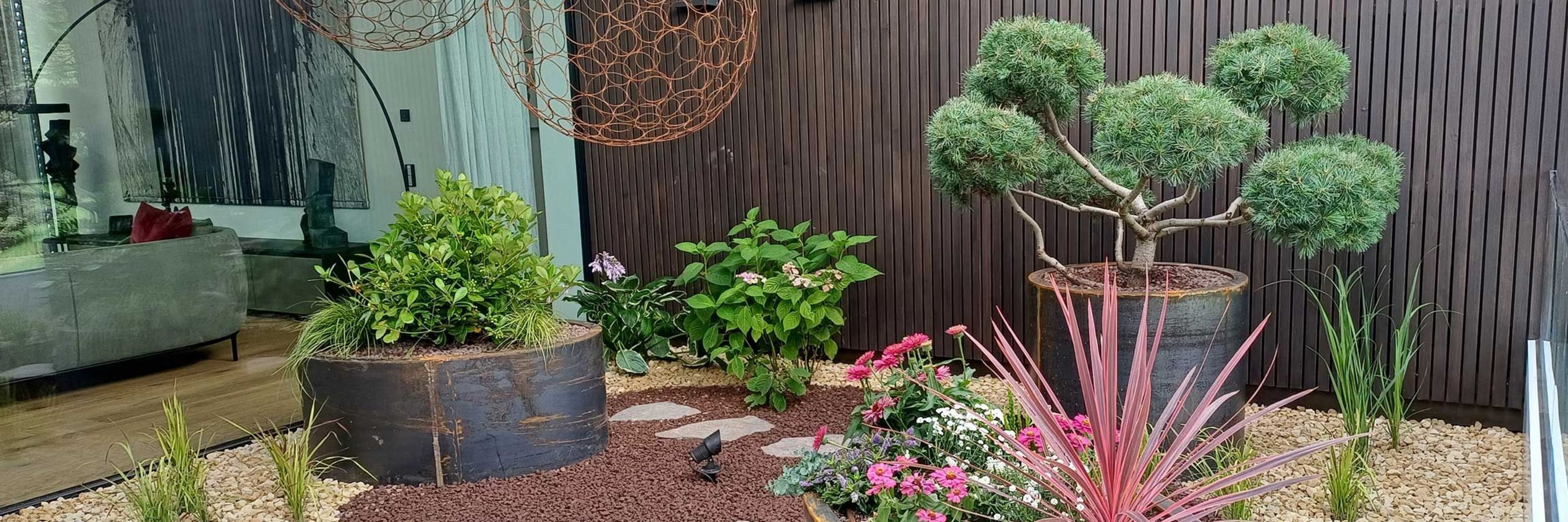 Arrangement mit Pflanzgefäßen und Trögen aus Cortenstahl