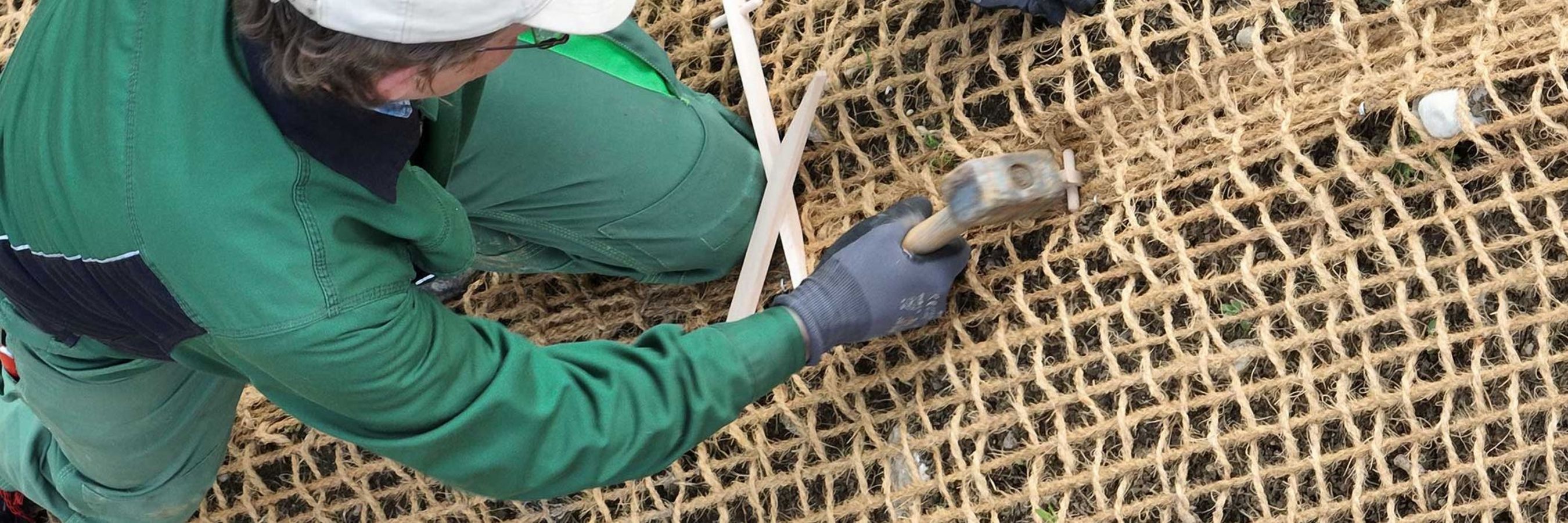 Arbeiter beim Anbringen von Kokosgewebe durch Einsatz eines Hammers