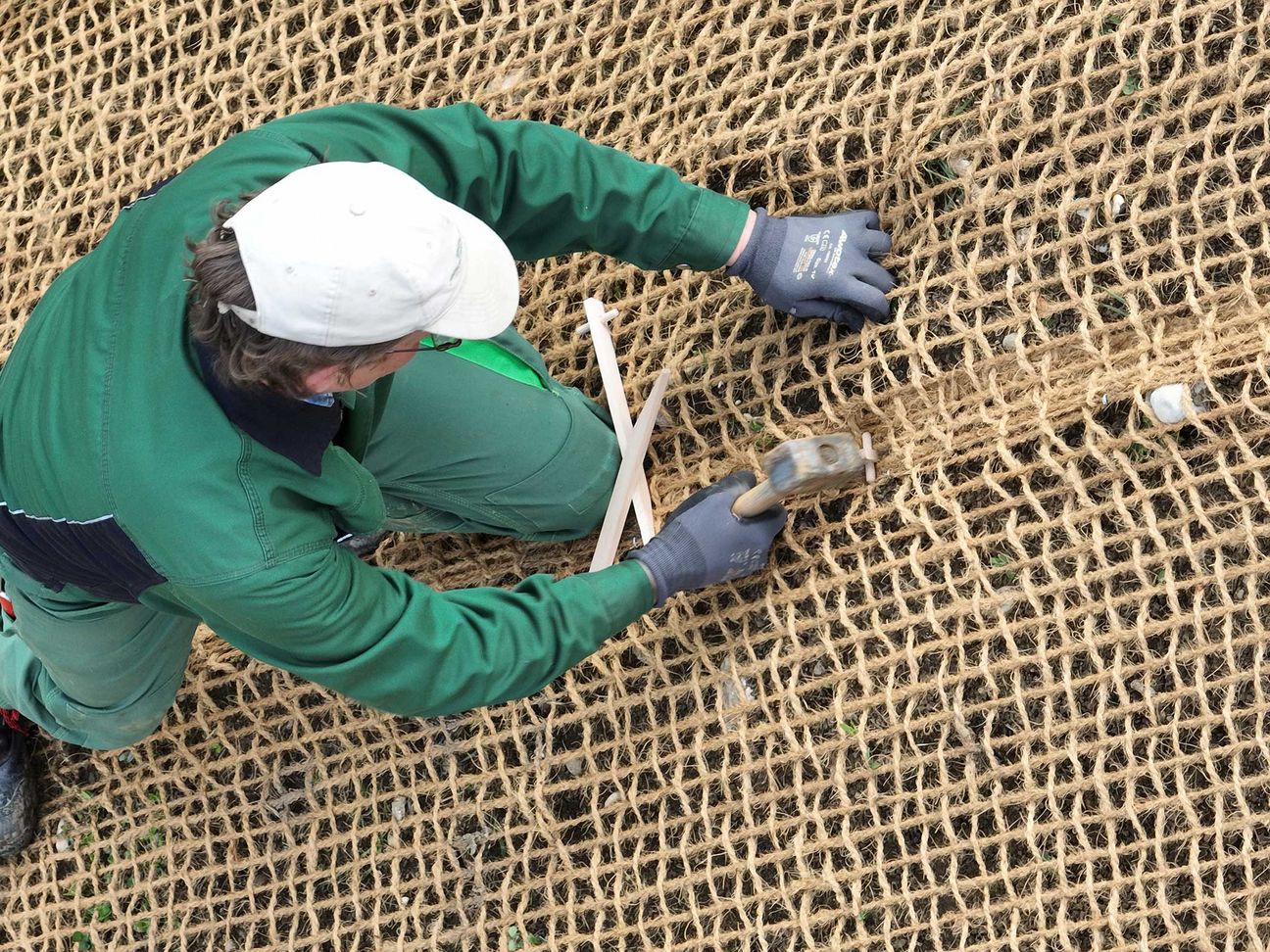 Arbeiter beim Anbringen von Kokosgewebe durch Einsatz eines Hammers